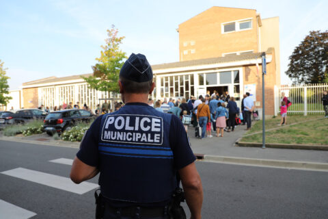 image représentant un policier municipal de dos surveillant une sortie d'école