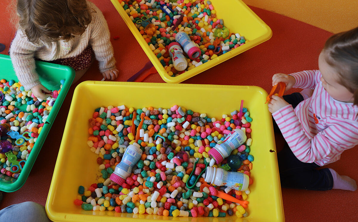 Photo de 2 enfants qui jouent avec des billes de couleurs