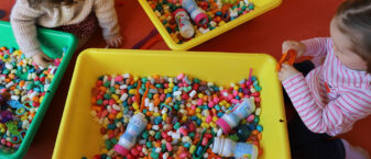 Photo de 2 enfants qui jouent avec des billes de couleurs
