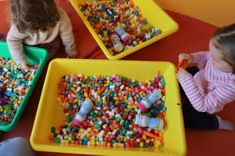 Photo de 2 enfants qui jouent avec des billes de couleurs