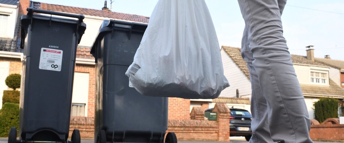 Image représentant un habitant plaçant un sac dans une poubelle à déchets ménagers.