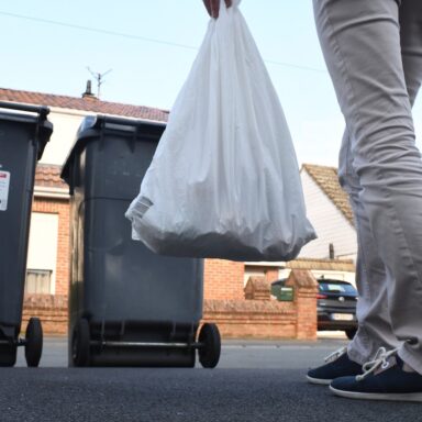 Image représentant un habitant plaçant un sac dans une poubelle à déchets ménagers.