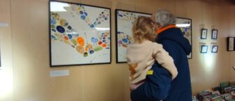 Image d'une personne de dos portant un enfant devant une exposition à la médiathèque Marguerite Yourcenar