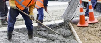 Photo d'un chantier où des ouvriers coulent du béton sur une route