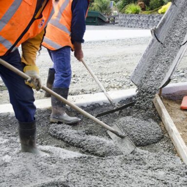 Photo d'un chantier où des ouvriers coulent du béton sur une route